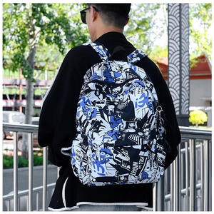 Outdoor shot of stylish backpack with blue graffiti print and small face charm
