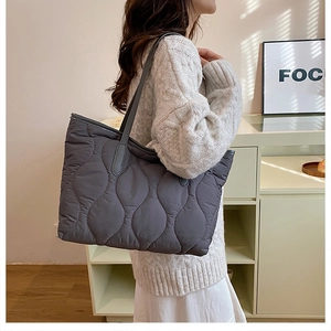 Detail of grey pleated tote bag with wavy stitching and smooth satin texture