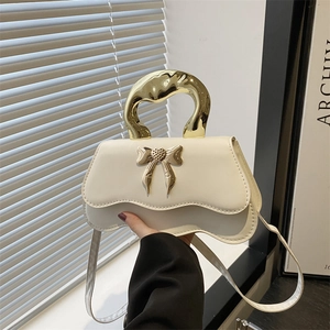 Chic cream leather handbag with wavy base, fluid gold metal handle, and bow detail