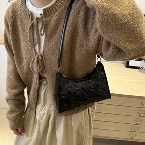 Minimalist black crescent shoulder bag with retro wave embossed texture and gold buckle