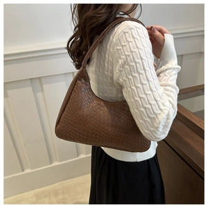 Detailed view of the brown woven texture and hobo silhouette on a women's underarm bag