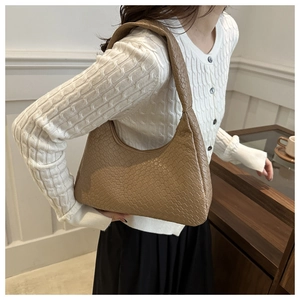 Detail of woven texture on a brown hobo bag worn with a white knit sweater