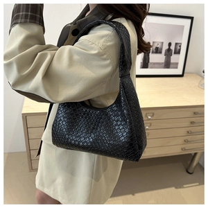 Detail of black woven crescent bag with crocodile texture and knot handle on model