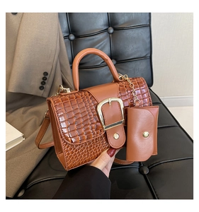 Brown crocodile pattern handbag with gold buckle and mini pouch on a leather seat