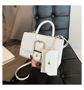 Detail of white crocodile embossed handbag with large gold buckle and mini pouch