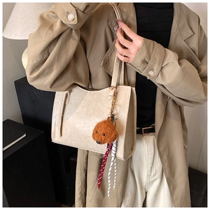 Dettaglio della borsa tote in pelle beige con ciondolo a forma di cane