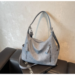 Detail showing the grainy suede texture and silver zipper pockets of this tote bag