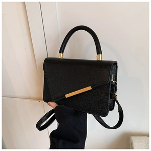 Detail of black crossbody bag featuring lychee texture and gold metal hardware trim