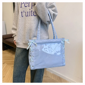 Borsa tote azzurra con tasca in PVC e fiocchi laterali indossata da una modella