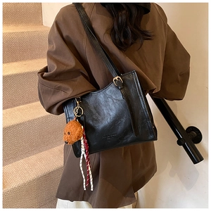 Dettaglio della borsa tote vintage nera con texture in pelle e ciondolo a forma di cane