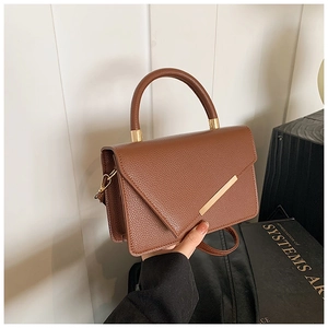 Detail of brown litchi pattern leather bag with gold metal trim and angled flap