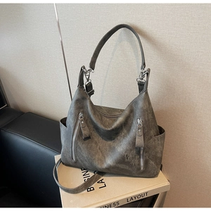 Detail view of charcoal gray matte leather tote with dual vertical zippers and side pockets