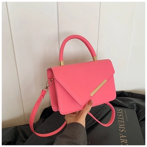 Detail of rose pink litchi grain leather bag with gold metal trim and curved handle