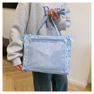 Dettaglio della borsa tote azzurra con finestra in PVC trasparente e fiocchi laterali
