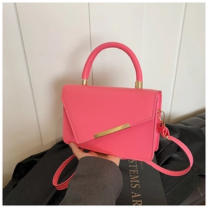 Detail of rose pink lychee leather handbag featuring geometric flap and gold metal hardware