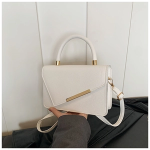 Detail of white lychee leather texture and golden metal hardware on a classic crossbody bag