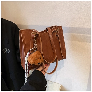 Dettaglio della borsa tote in ecopelle marrone con ciondolo a cane e corda a strisce