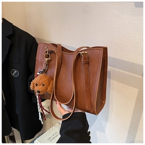 Dettaglio borsa tote marrone vintage con texture in pelle e ciondolo a forma di orso