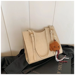 Dettaglio borsa tote beige in ecopelle con fibbia dorata e charm a forma di orsetto
