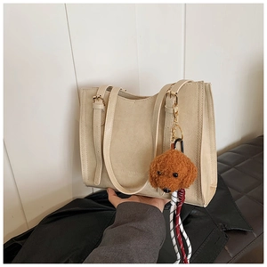 Dettaglio della grande borsa tote crema con goffratura FASHION & BAGS e ciondolo a orsetto