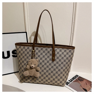 Close-up of winter tote bag featuring vintage pattern and cute plush bear charm