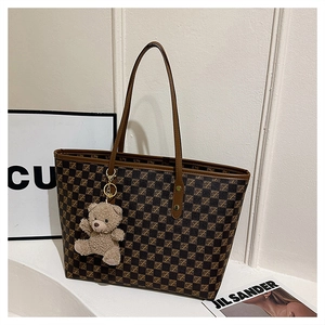 Detail of the checkered tote bag featuring a plush bear charm and sleek brown handles