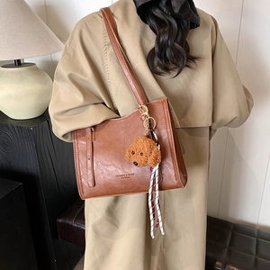 Borsa tote vintage in pelle marrone con ciondolo a cane e nastro su trench kaki