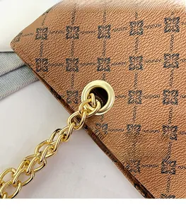 Detail of brown embossed leather tote with floral pattern and gold chain hardware