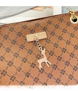 Detail of brown monogram leather bag with gold D-ring and deer charm accessory