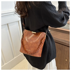 Detailed macro view of the brown retro oiled leather bucket bag with woven handle and clasp