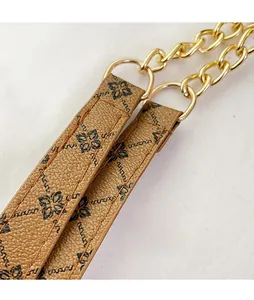 Detail of brown lychee leather shoulder strap with golden chain and floral pattern