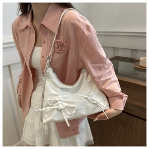 Detail of white ruched tote bag featuring decorative bows and silver chain strap