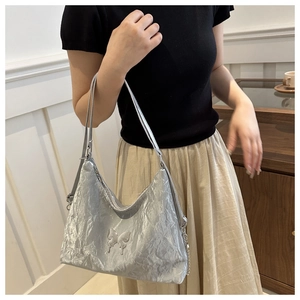 Détail du sac hobo argenté métallisé avec papillon 3D et fine bandoulière élégante