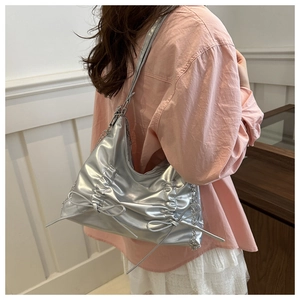 Detail of silver metallic tote bag with decorative bow and stylish metal chain strap