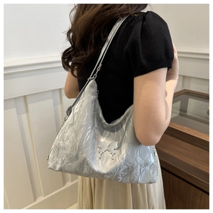 Gros plan d'un sac Hobo plissé argenté avec un emblème papillon et une bandoulière chaîne