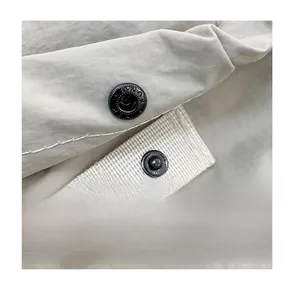 Detail of high-quality black metal snap button on beige durable twill backpack fabric