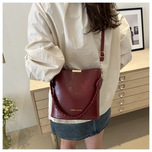 Detail of wine red leather bucket bag with woven handle and gold-tone hardware