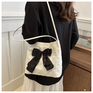 Detail der weißen Beuteltasche mit schwarzer Schleife und Sterntextur für Damen