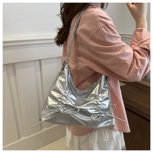 Detail of silver metallic hobo bag with delicate bows and stylish side chain decoration