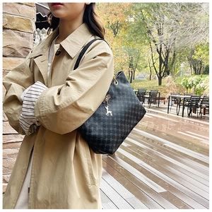 Close-up of black tote bag with quilted cross pattern and golden deer charm detail