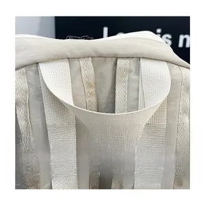 Detail of reinforced padded handle and shoulder strap stitching on beige backpack