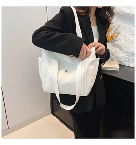Detailed side view of a large white canvas tote bag with shoulder straps and metal snaps