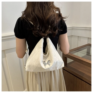 Détail du sac à bandoulière en satin blanc avec boucle papillon argentée sur un modèle