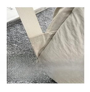 Close-up of reinforced stitching on minimalist beige nylon backpack with durable texture