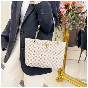 Detail of cream tote bag with cross pattern, gold chain strap, and deer charm