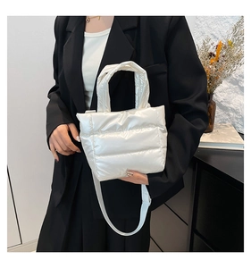 Gros plan d'un sac seau matelassé blanc brillant porté par un mannequin en costume noir
