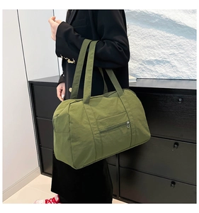 Detail view of a spacious olive green nylon tote bag featuring durable metal zippers
