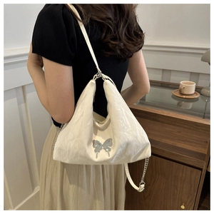 Détail du sac bandoulière plissé blanc avec papillon argenté et bandoulière en chaîne