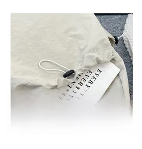 Detail of off-white nylon backpack front pocket with elastic drawstring and toggle