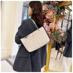 Detail of off-white tote bag with geometric patterns and golden chain strap on model